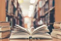 Love story book with open page of literature in heart shape and stack piles of textbooks on reading desk in library, school study