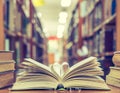 Love story book with open page of literature in heart shape and stack piles of textbooks on reading desk in library, school study