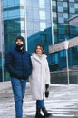 Love story of couple walking in city. Young business man in a blue jacket with a beard. And a cute woman in long coat Royalty Free Stock Photo