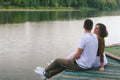 Love story of funny couple walking near river in hard rainfall with umbrella. cute man and woman in white skirt, yellow sweater Royalty Free Stock Photo