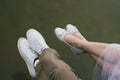 Love story of funny couple walking near river in hard rainfall with umbrella. cute man and woman in white skirt, yellow sweater Royalty Free Stock Photo