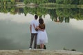 Love story of funny couple walking near river in hard rainfall with umbrella. cute man and woman in white skirt, yellow sweater Royalty Free Stock Photo