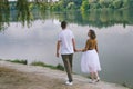 Love story of funny couple walking near river in hard rainfall with umbrella. cute man and woman in white skirt, yellow sweater Royalty Free Stock Photo