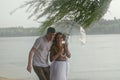 Love story of funny couple walking near river in hard rainfall with umbrella. cute man and woman in white skirt, yellow sweater Royalty Free Stock Photo