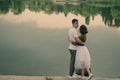 Love story of funny couple walking near river in hard rainfall with umbrella. cute man and woman in white skirt, yellow sweater Royalty Free Stock Photo