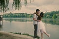 Love story of funny couple walking near river in hard rainfall with umbrella. cute man and woman in white skirt, yellow sweater Royalty Free Stock Photo