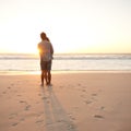 Love at sunset. Rearview shot of a young couple enjoying the sunset at the beach. Royalty Free Stock Photo
