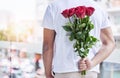 Love, surprise and man with roses behind back for date, romance and hope for valentines day. Romantic confession, floral