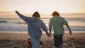 Love teenagers running sandy beach evening back view. Carefree couple enjoying Royalty Free Stock Photo