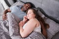 Multiracial couple laying at the bed indoors at home and hugging while sleeping
