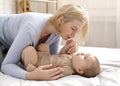 Loving blonde mother caressing her baby boy on bed Royalty Free Stock Photo