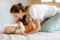 Loving young mother caressing her cute baby boy at bedroom Royalty Free Stock Photo