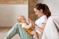 Loving young mother caressing her cute baby boy, home interior Royalty Free Stock Photo