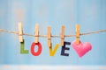 LOVE text and pink heart shape decoration hanging on line with copy space for text on blue wooden background. Love, Wedding, Royalty Free Stock Photo