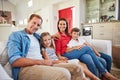 They love their family moments. Portrait of smiling parents sitting with their young son and daughter on their living Royalty Free Stock Photo