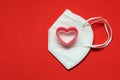 Love in times of pandemic and covid, kn95 protection mask with hearts on red background, Valentine`s day