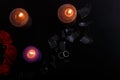 Love triangle and broken relationship concept. Wedding rings and three burning candles on black background. Flat lay, top view Royalty Free Stock Photo