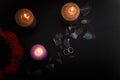 Love triangle and broken relationship concept. Wedding rings and three burning candles on black background. Flat lay Royalty Free Stock Photo