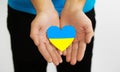 Ukrainian flag in the shape of a heart in the hands of a man. Ukrainian symbols, the flag of Ukraine -