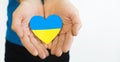 Love Ukraine concept. Ukrainian flag in the shape of a heart in the hands of a man. Ukrainian symbols,