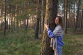 Unity with nature: young calm girl hugging pine tree trunk with closed eyes walking in autumn forest