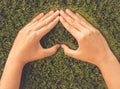 Retro woman hand in shape of heart on green grass background. Royalty Free Stock Photo