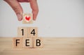 Love valentine`s day conceptman hand holding the heart to put on the cube wooden to mean the love on valentines day Royalty Free Stock Photo