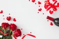 Flat lay composition made of red roses with ribbon, wine bottle, gift box, red hearts on white background Royalty Free Stock Photo