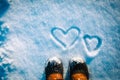 Love winter concept- feet in snow boots and heart in nature