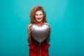 Love woman smiling holding red heart shaped balloon. Cute beautiful young woman in love. Caucasian female model in red dress isola Royalty Free Stock Photo