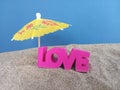 Love word on beach sand with a yellow umbrella Royalty Free Stock Photo