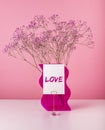 Love word on card with pink flower bunch on pink. Valentine s day