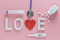 LOVE word made from medicine pills, red heart shape pouring out of white bottle and stethoscope, needle ,temperature Royalty Free Stock Photo