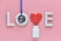 LOVE word made from medicine pills, red heart shape pouring out of white bottle and stethoscope, on pink background. Royalty Free Stock Photo