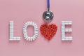LOVE word made from medicine pills, red heart shape and stethoscope, on pink background. Concept of Valentine`s Day Royalty Free Stock Photo