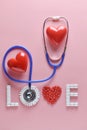 LOVE word made from medicine pills, red heart shape and stethoscope, on pink background. Royalty Free Stock Photo