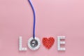 LOVE word made from medicine pills, red heart shape and stethoscope, on pink background. Royalty Free Stock Photo