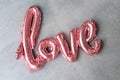 Love word from pink inflatable balloon on grey concrete background. The concept of romance, Valentine`s Day. Love rose Royalty Free Stock Photo