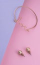 Love word shaped bracelet with golden earrings on pink and purple background