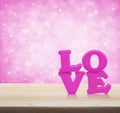 Love word toy on wooden table over light pink heart bokeh background, valentine concept Royalty Free Stock Photo