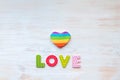 LOVE word in wood letters and rainbow heart shape pillow on wood vintage board. Valentines day concept. Mockup for LGBT Royalty Free Stock Photo