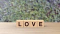 Love word Wooden cubes on table over background leaves green HD, mock up, template, love for one`s partner, good friends, no war Royalty Free Stock Photo