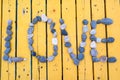 Love word written on a line of stones on a wooden background. The yellow wooden pavement made of boards on the seashore. Greting