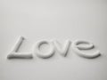 LOVE written in snow with soft shadows on white surface. Royalty Free Stock Photo