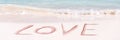 Love written on the white sand of an idyllic beach panoramic Valentines day banner Royalty Free Stock Photo