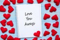 LOVE YOU AWAYS word on notebook with pink heart shape decoration on blue wooden table background. Wedding, Romantic and Happy Royalty Free Stock Photo