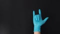 The love-you gesture or I love you hand sign with hand wearing blue glove on black background Royalty Free Stock Photo