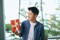 With love for you. Good looking young man in blue jeans shirt holding a gift box Royalty Free Stock Photo