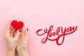 Love You hand lettering. woman hans holds red heart on a pink background Top view flat lay trendy