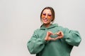 Love you. Portrait of attractive romantic young woman with brown hair standing and making heart with hands, smiling Royalty Free Stock Photo